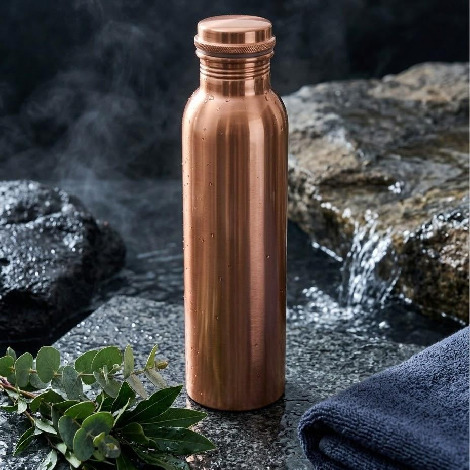 Pure · Smooth Copper: polished 1 L copper bottle on wet dark stone with eucalyptus