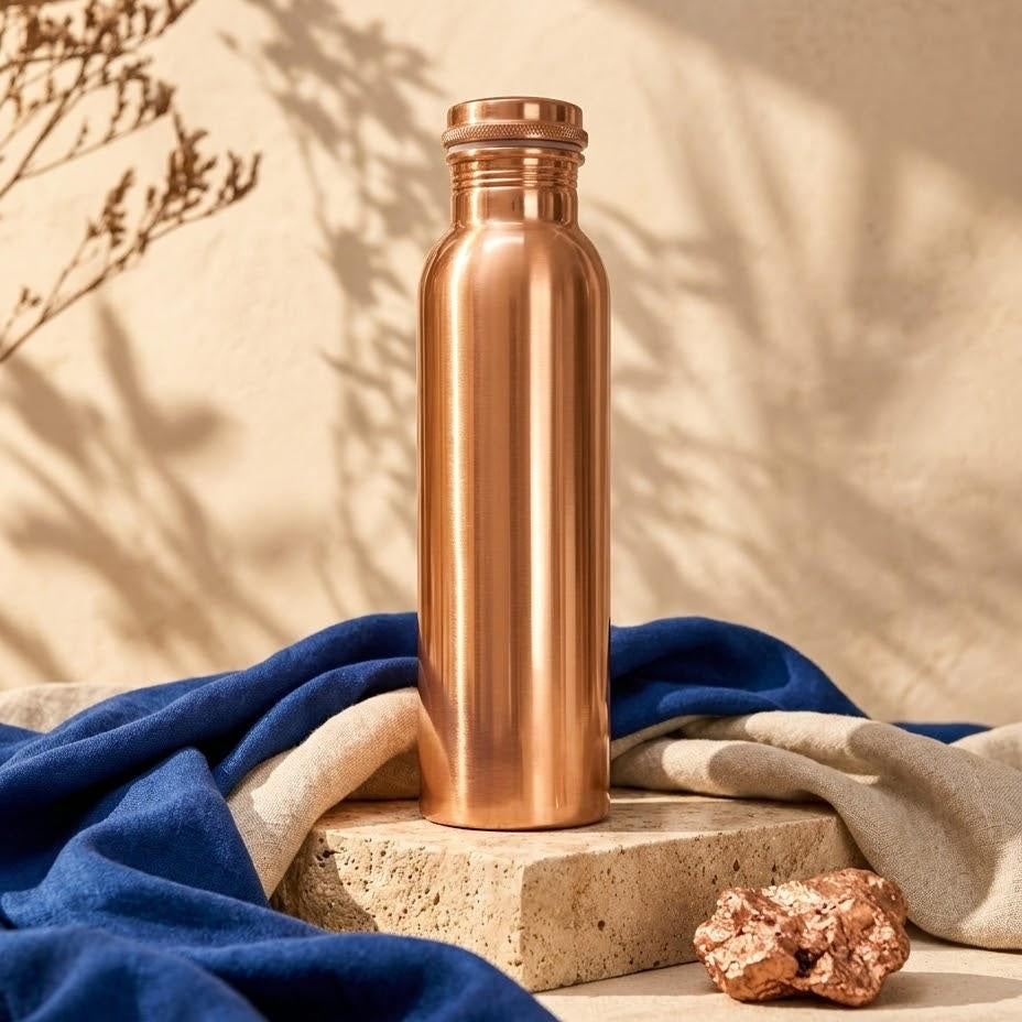 Pure · Smooth Copper: polished 1 L copper bottle on travertine with linen and raw copper